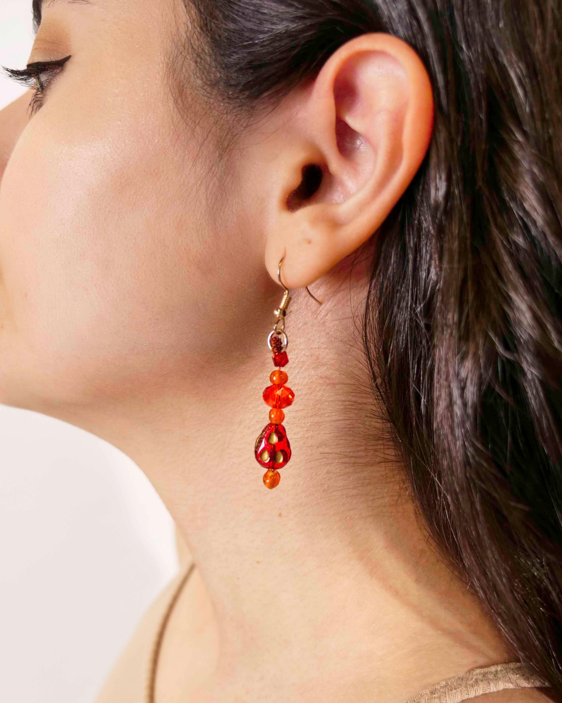 A handmade red and orange crystal beaded pair of dangle drop earrings with red glass charms.