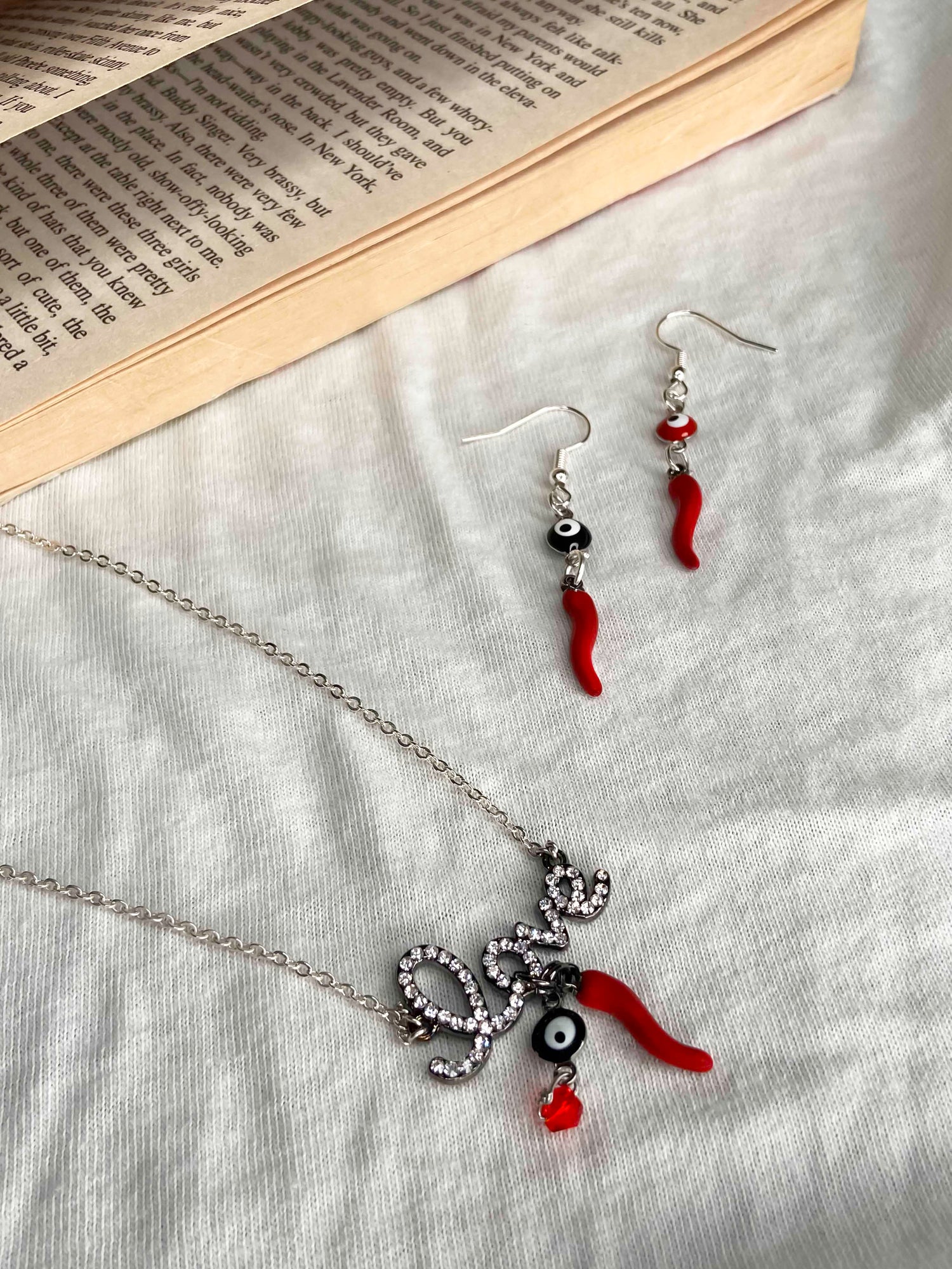 A matching set of a handmade pair of earrings and necklace made using evil eye and chili pepper charms.
