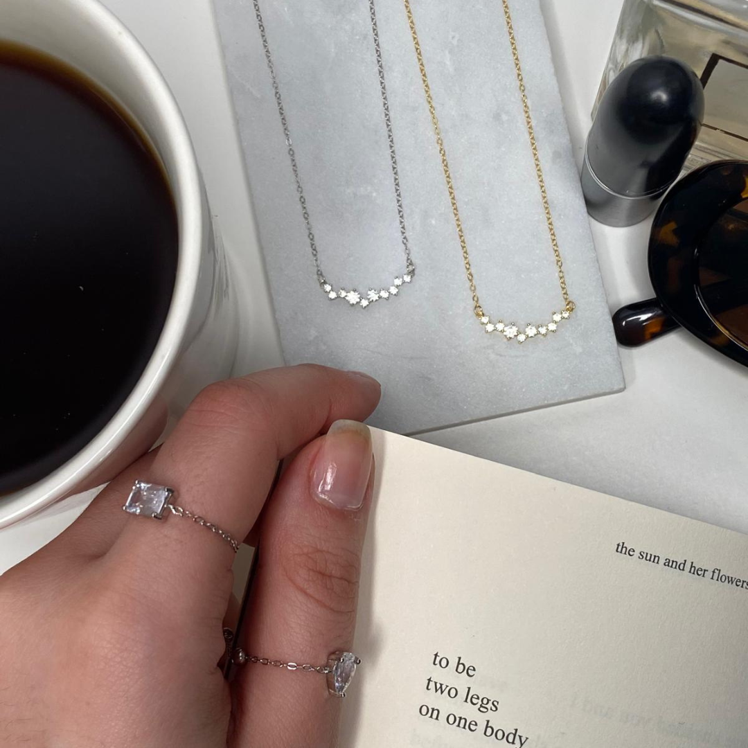 coffee pictured with two sterling necklaces, two sterling silver rings, and a lit candle for relaxing morning vibes.