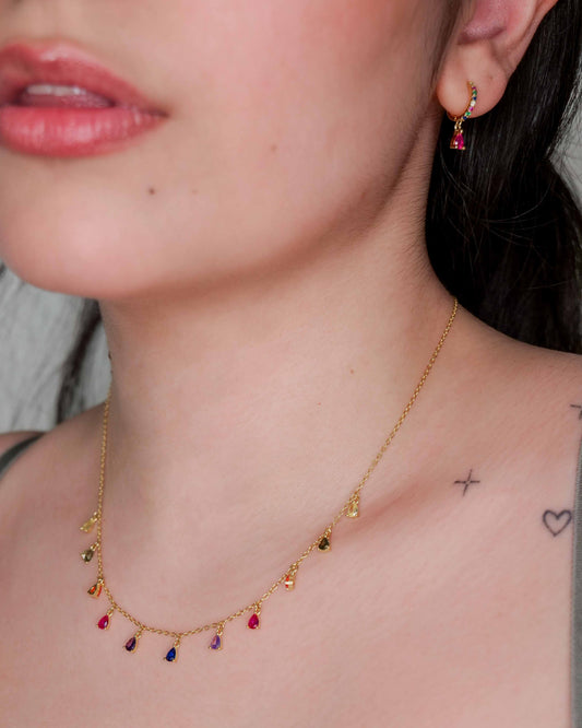 Close-up of a person wearing a gold necklace with colorful beads.