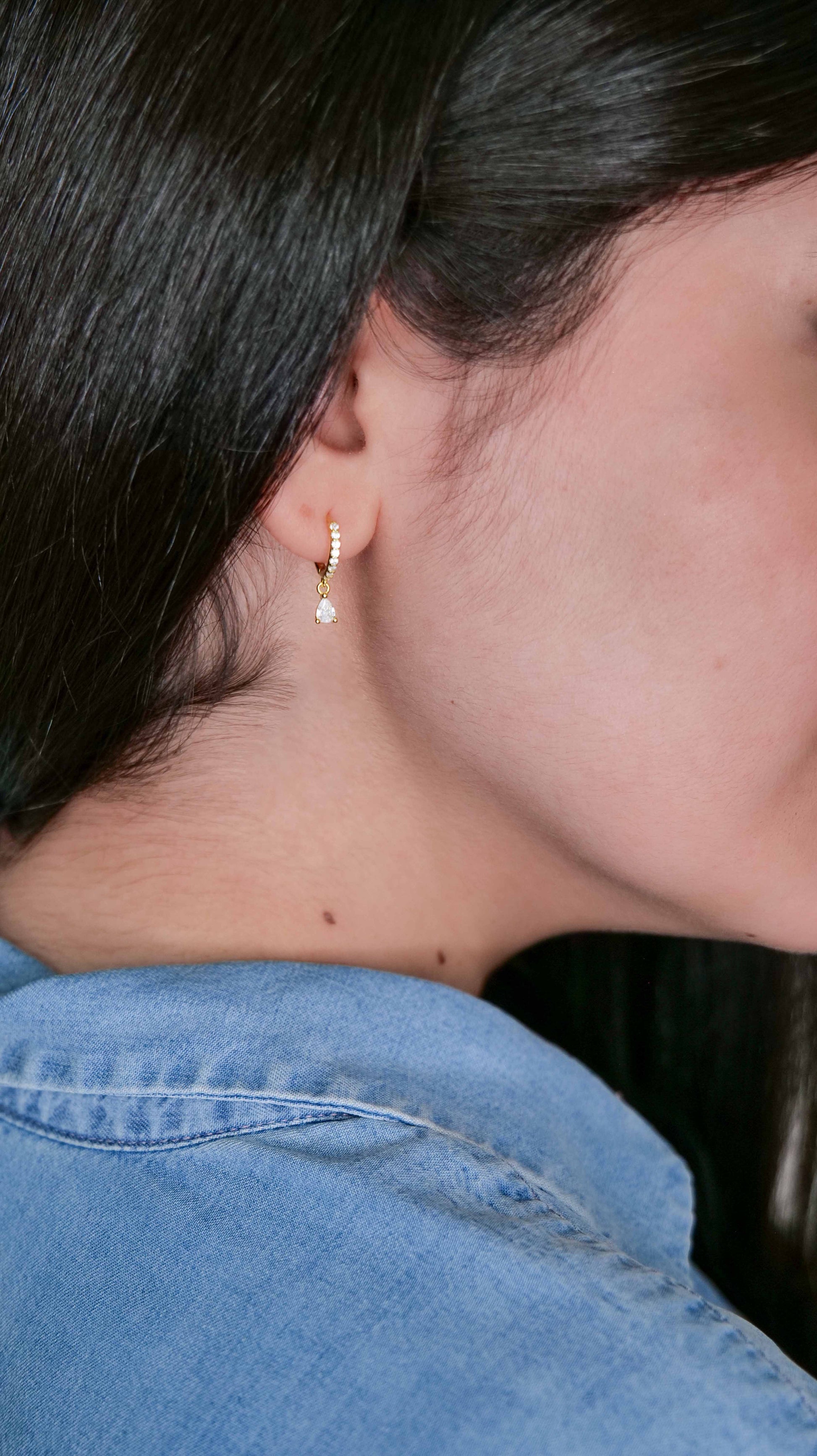 Close-up of a person wearing a pearl earring with a blurred background