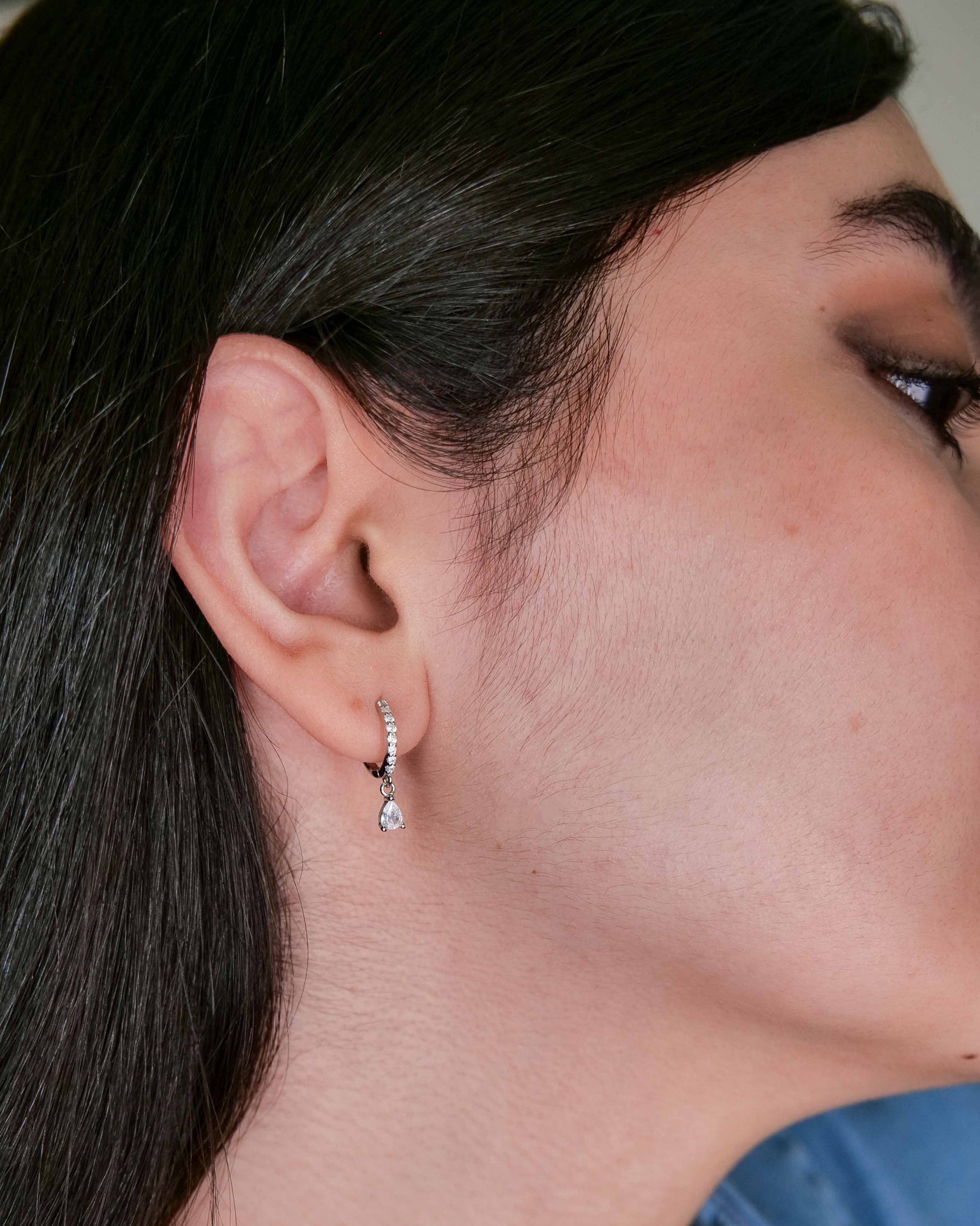 Close-up of a person wearing a diamond earring with a blurred background