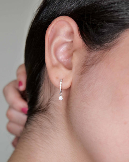 Close-up of an ear wearing a diamond earring with a blurred background