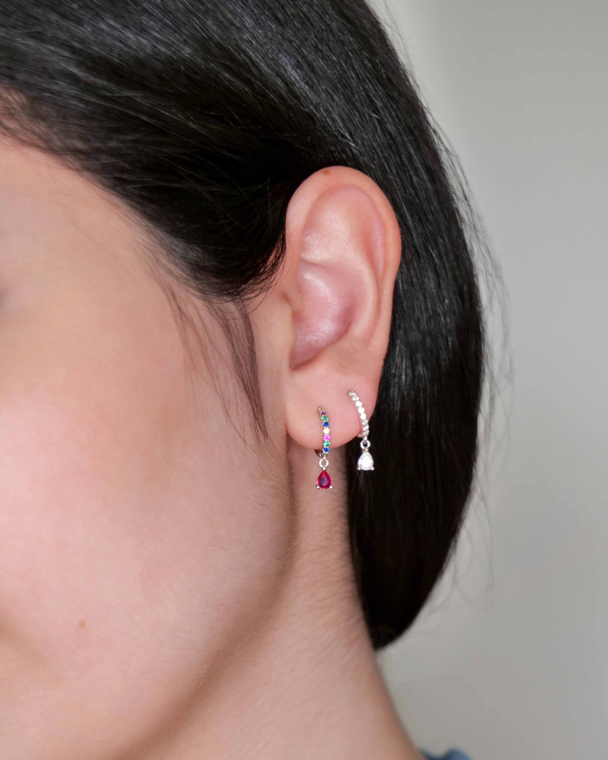 Close-up of an ear wearing a small earring with a neutral background