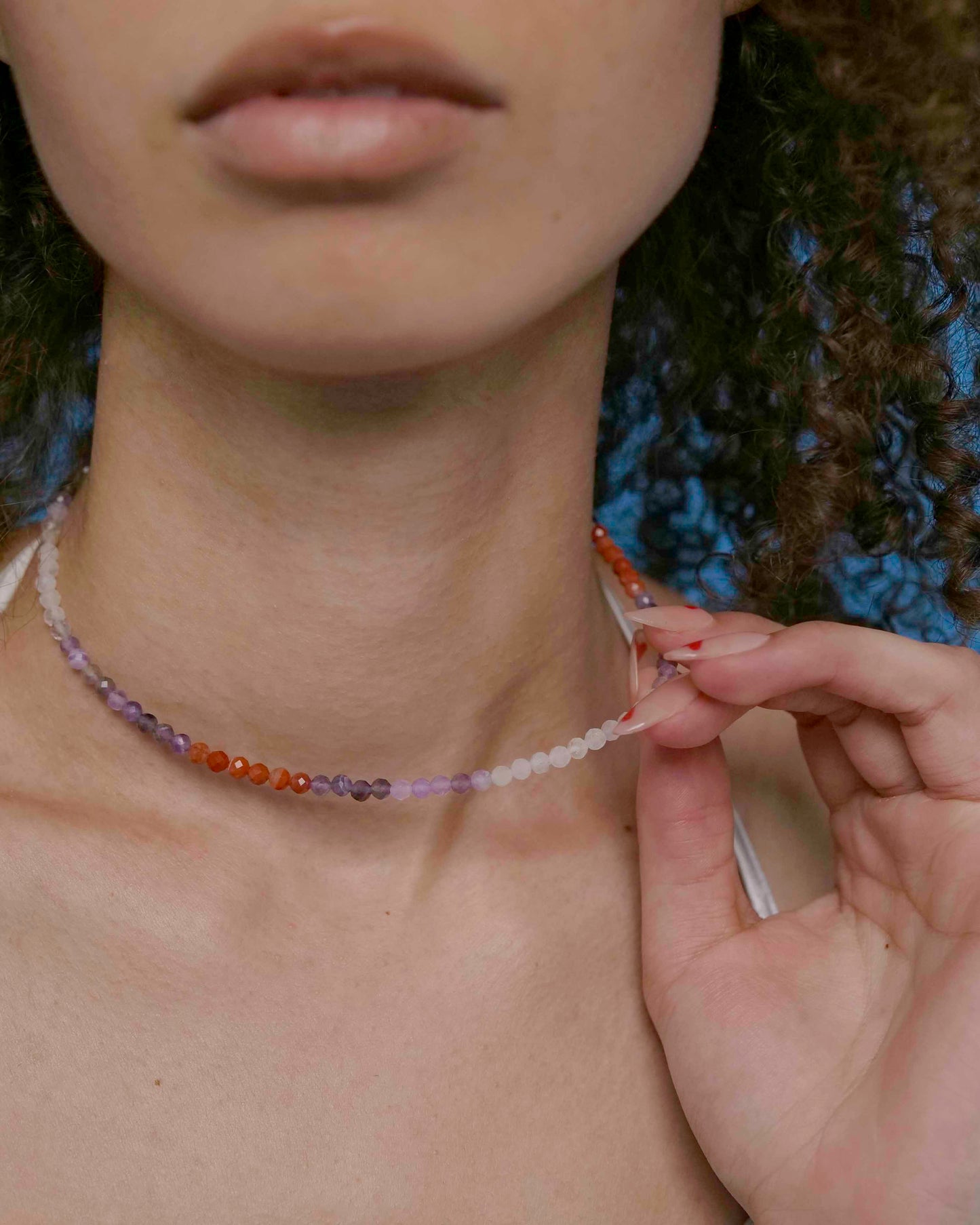 A person wearing a multicolored beaded choker necklace with a sterling silver clasp.