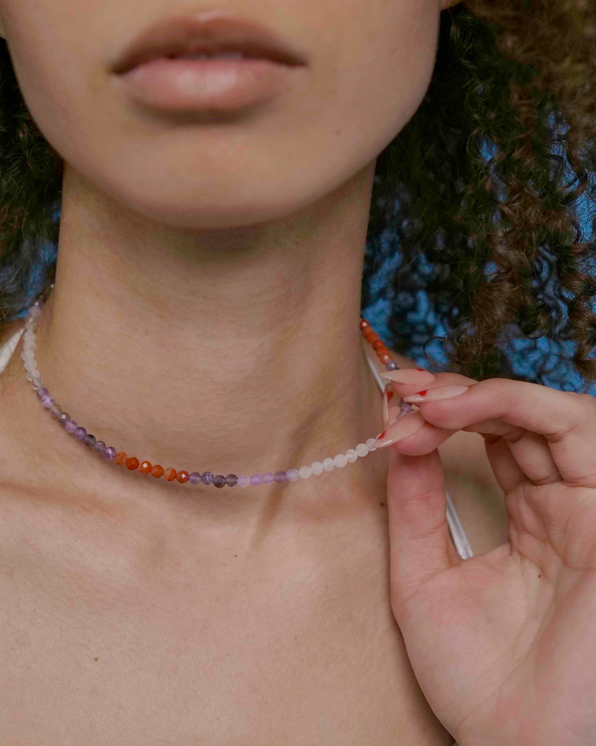 A person wearing a multicolored beaded choker necklace with a sterling silver clasp.