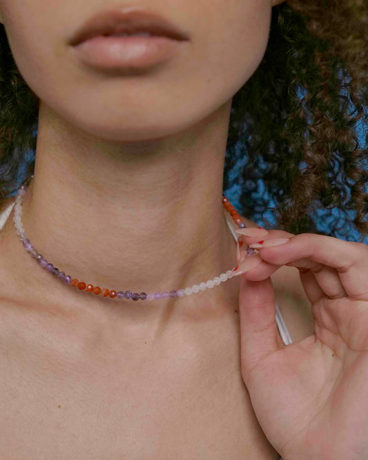 A person wearing a multicolored beaded choker necklace with a sterling silver clasp.