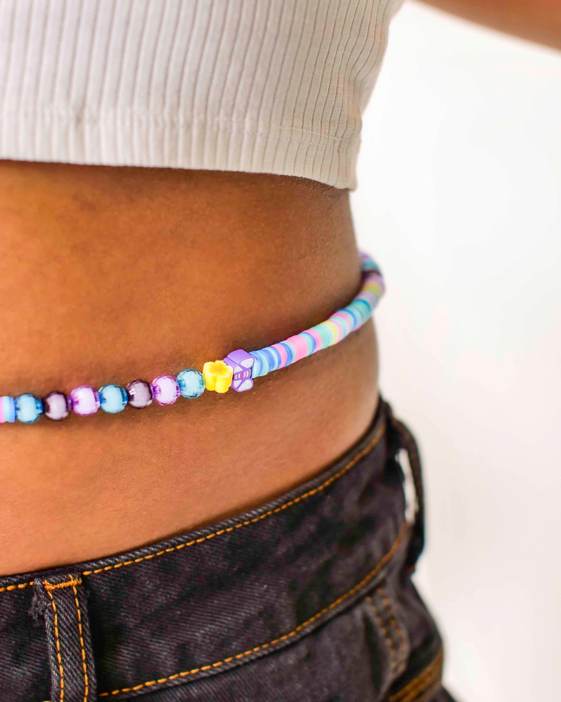 Handmade beaded belly chain made using multicolor flat rubber beads, flower and butterfly charms, and Discoball-like beads.
