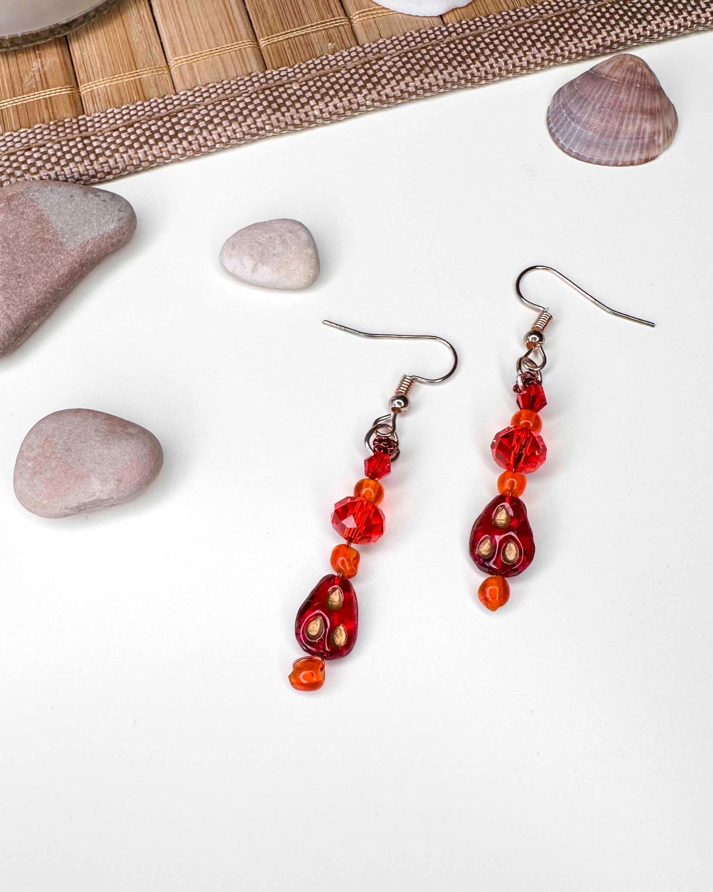 A handmade red and orange crystal beaded pair of dangle drop earrings with red glass charms.