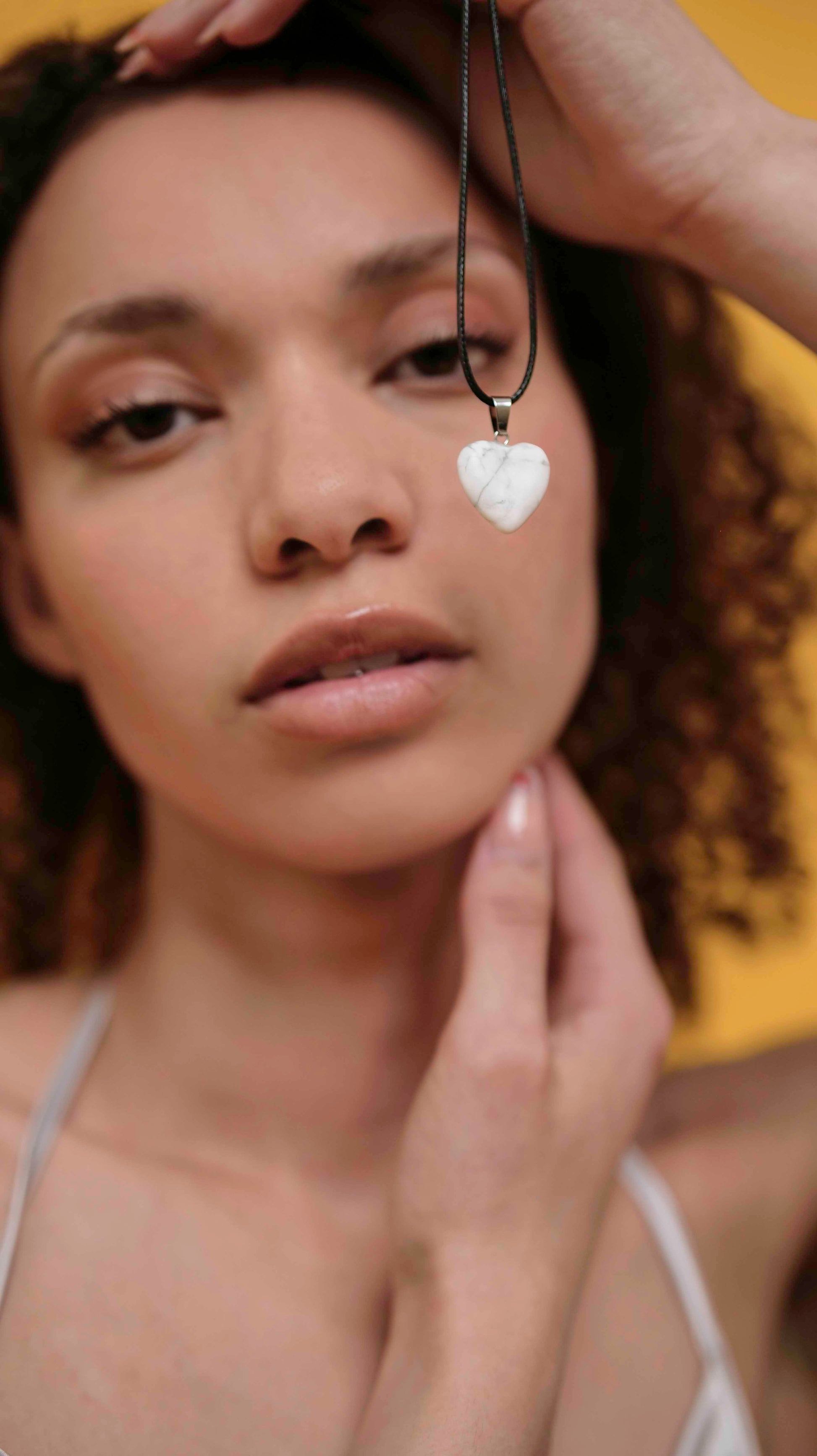 A handmade howlite heart pendant necklace with a black vegan leather string.