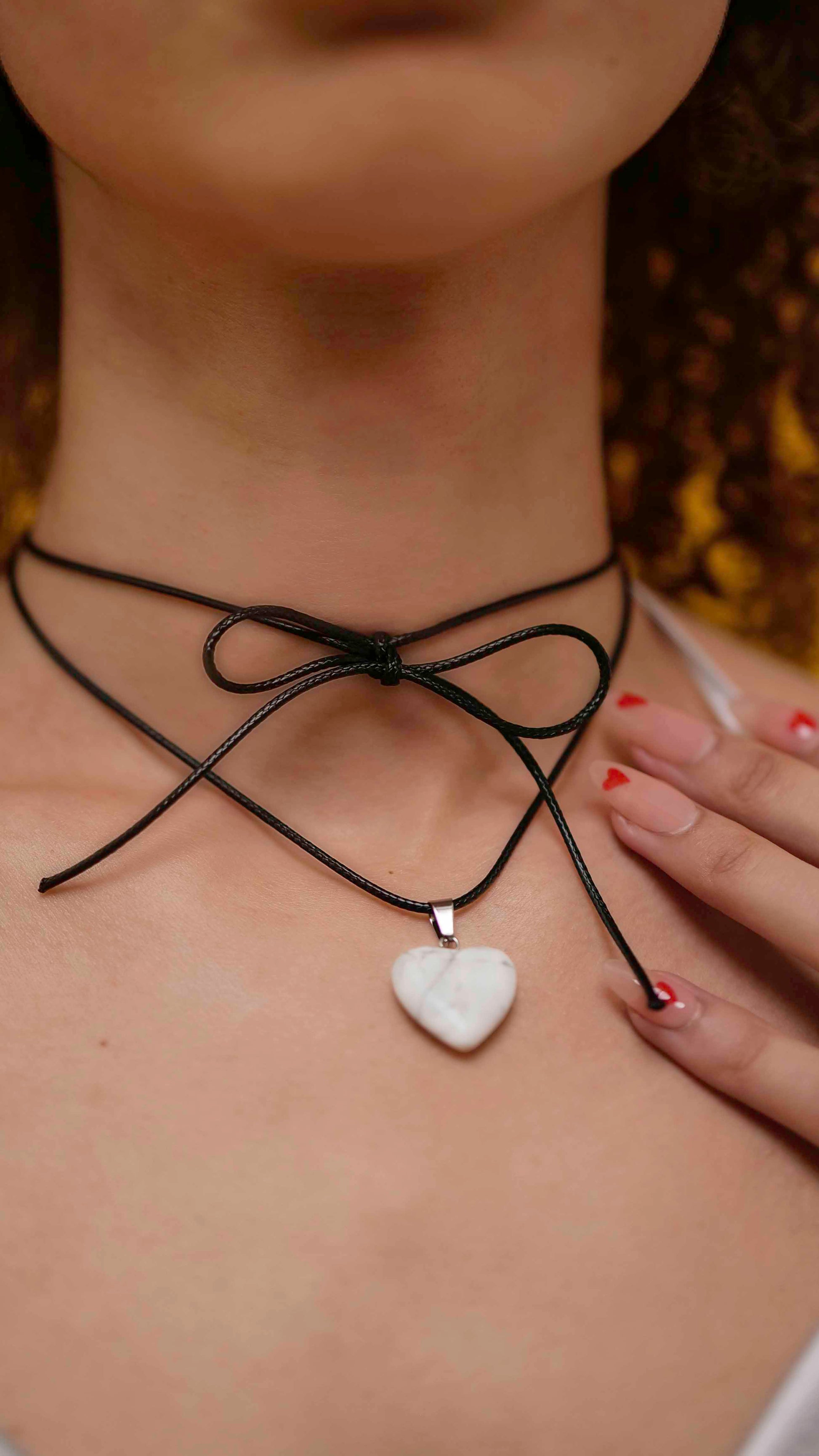 A handmade howlite heart pendant necklace with a black vegan leather string.