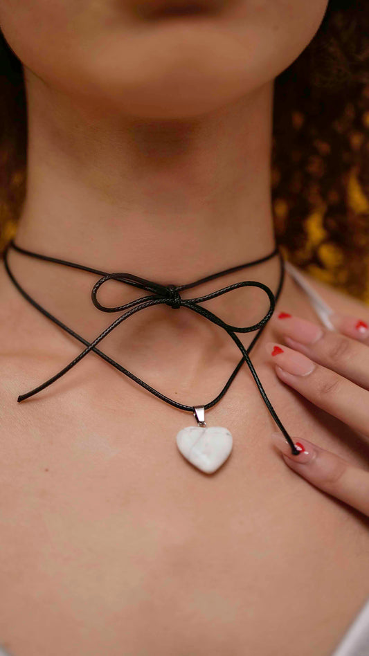 A handmade howlite heart pendant necklace with a black vegan leather string.