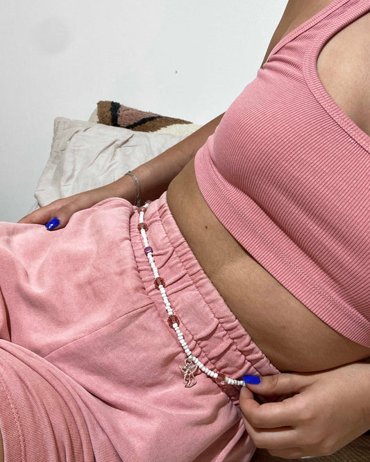 White glass beads with large light pink crystal and circle beads, handcrafted into a belly chain with silver angel charm