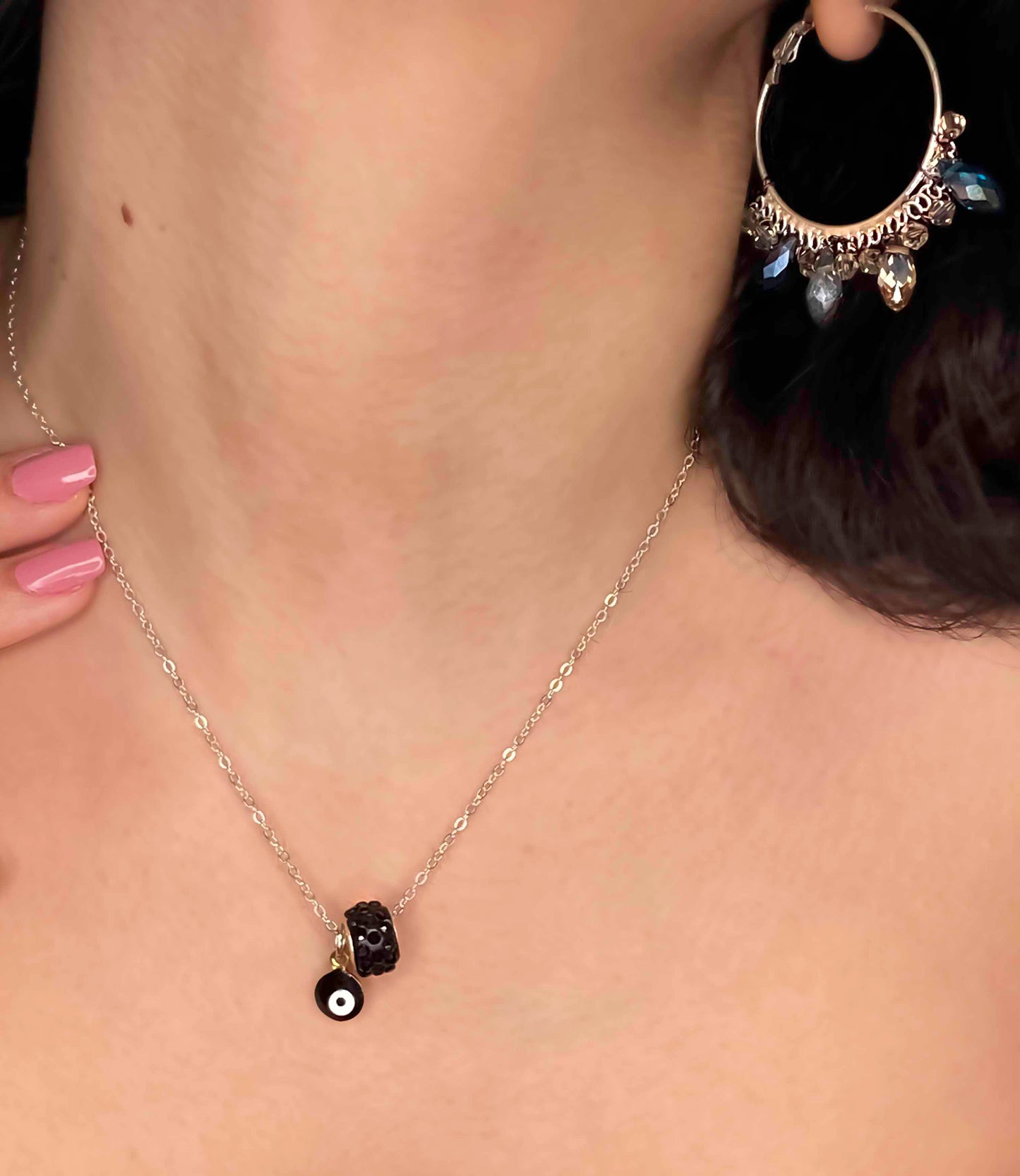A handmade matching set of a pair of crystal beaded hoop earrings and a black evil eye pendant necklace.