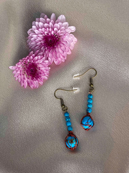 A pair of handcrafted wire-wrapped and beaded turquoise earrings. 