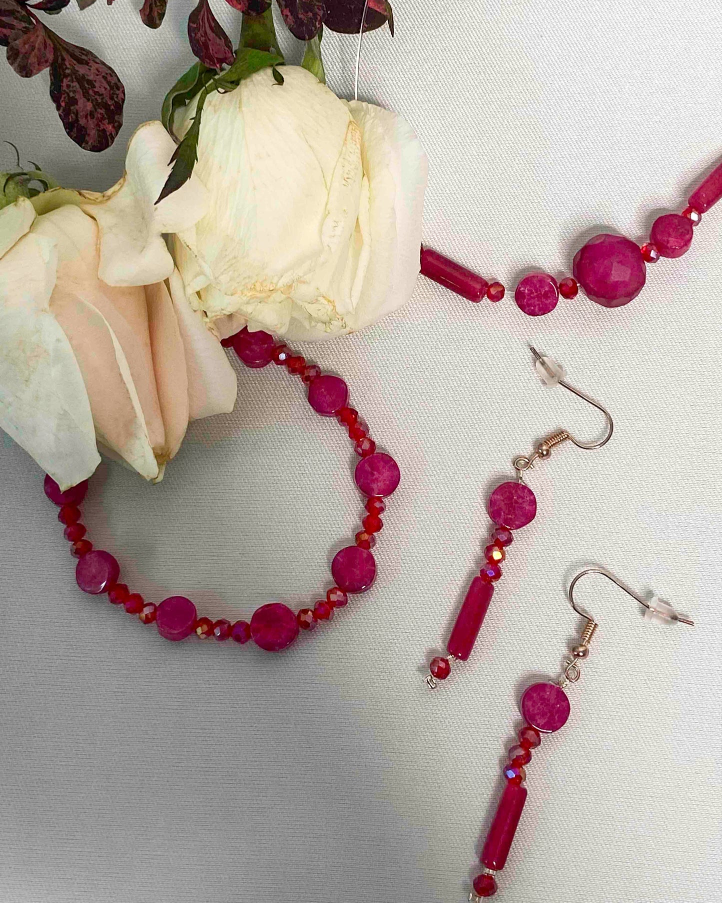 A set of handmade red crystal bead and pink rubellite stone bracelet, pendant necklace, and dangle drop earrings.