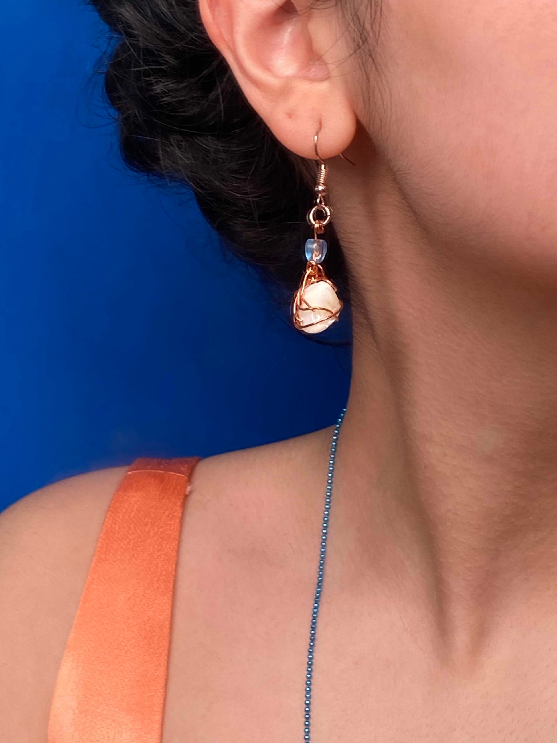 A pair of handmade copper wire wrapped large freshwater pearl earrings.