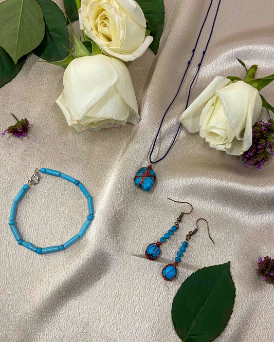 A pair of handcrafted wire-wrapped and beaded turquoise earrings, a matching pendant necklace, and beaded bracelet.