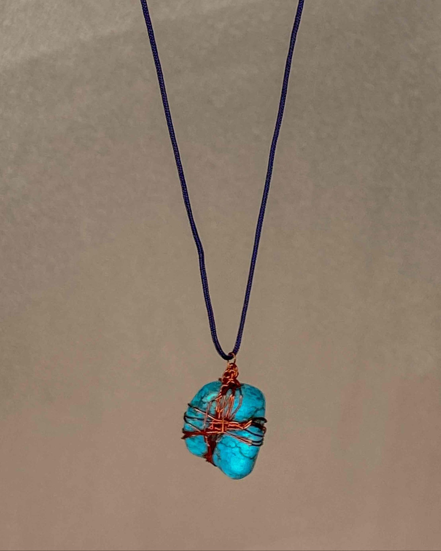 A handcrafted wire-wrapped turquoise stone pendant necklace.