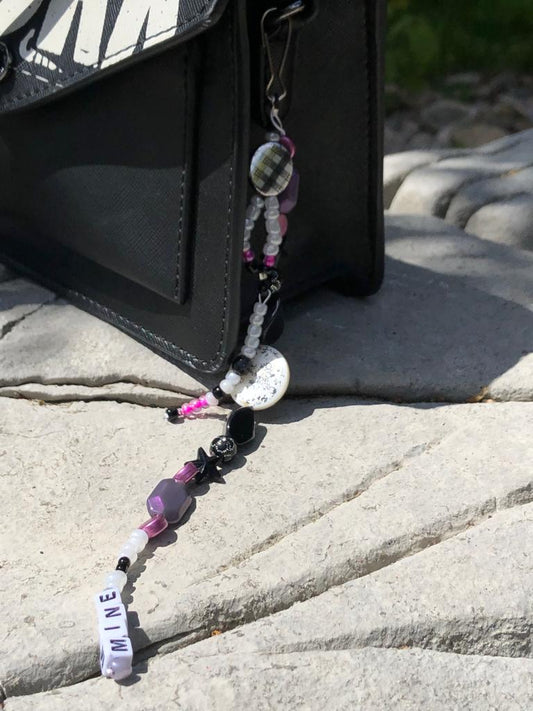 White, black, purple and pink beaded bag charm. Handcrafted with black stars, a coin floral print charm, and mine beaded using letter beads.