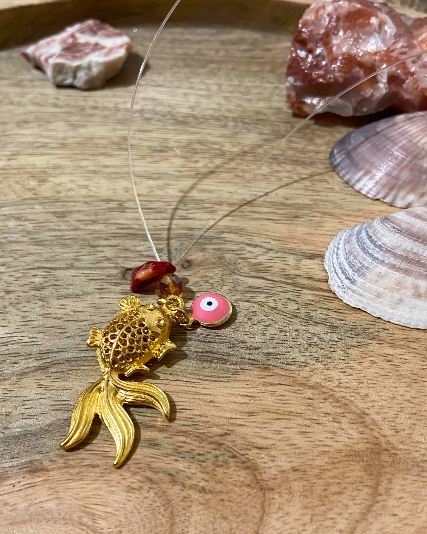 handmade goldfish charm pendant necklace with evil eye charm and crystal pieces.
