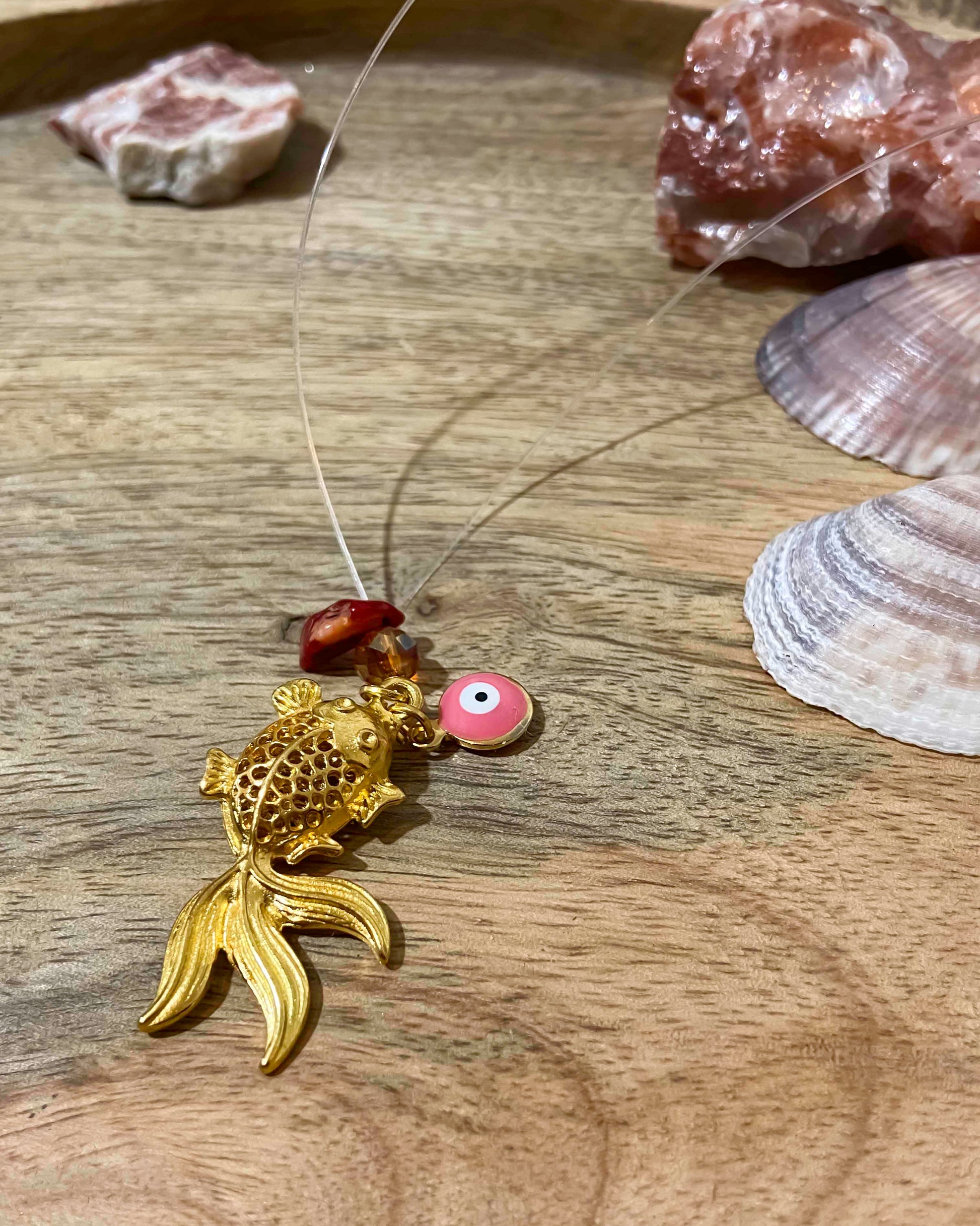 handmade goldfish charm pendant necklace with evil eye charm and crystal pieces.