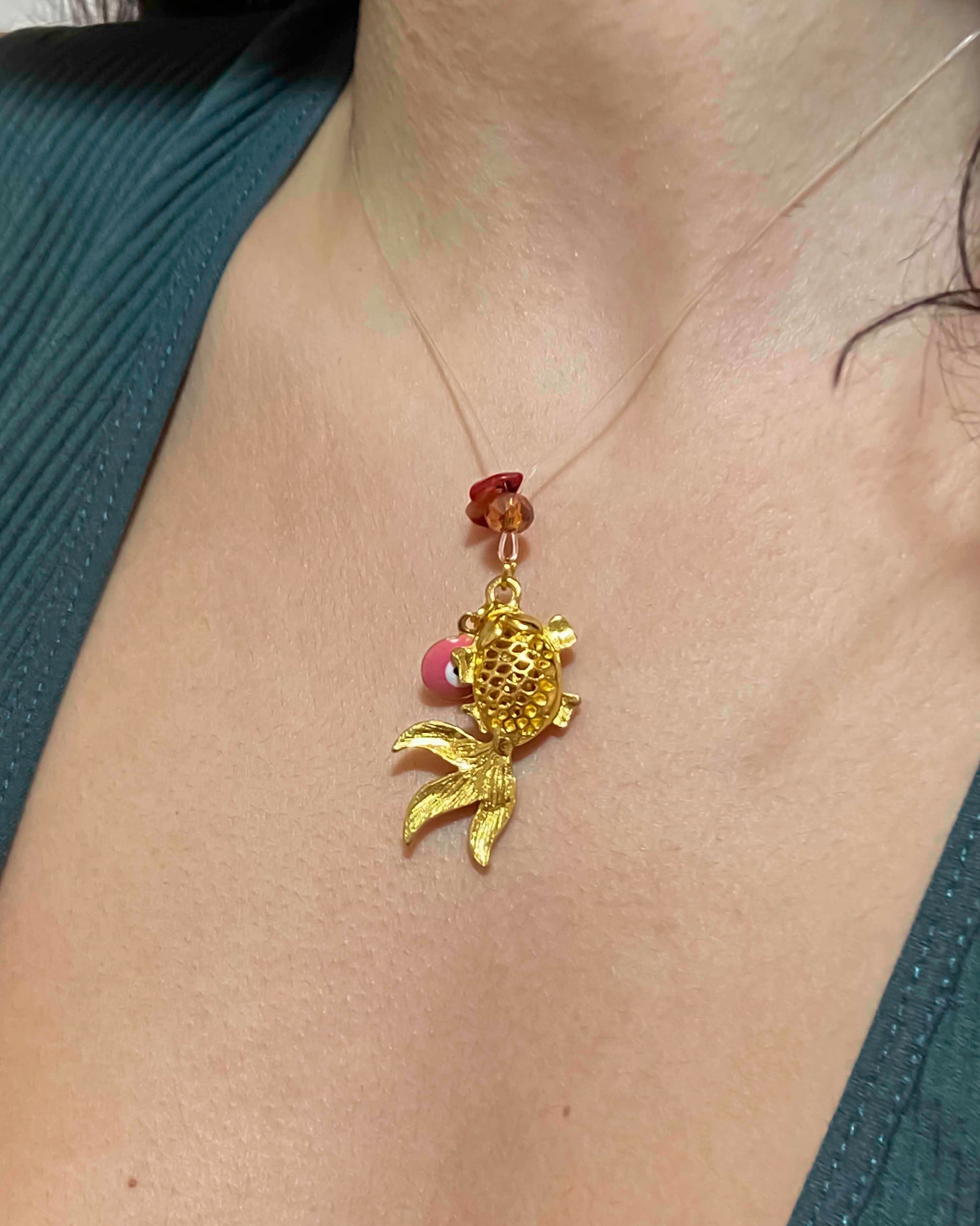 handmade goldfish charm pendant necklace with evil eye charm and crystal pieces.