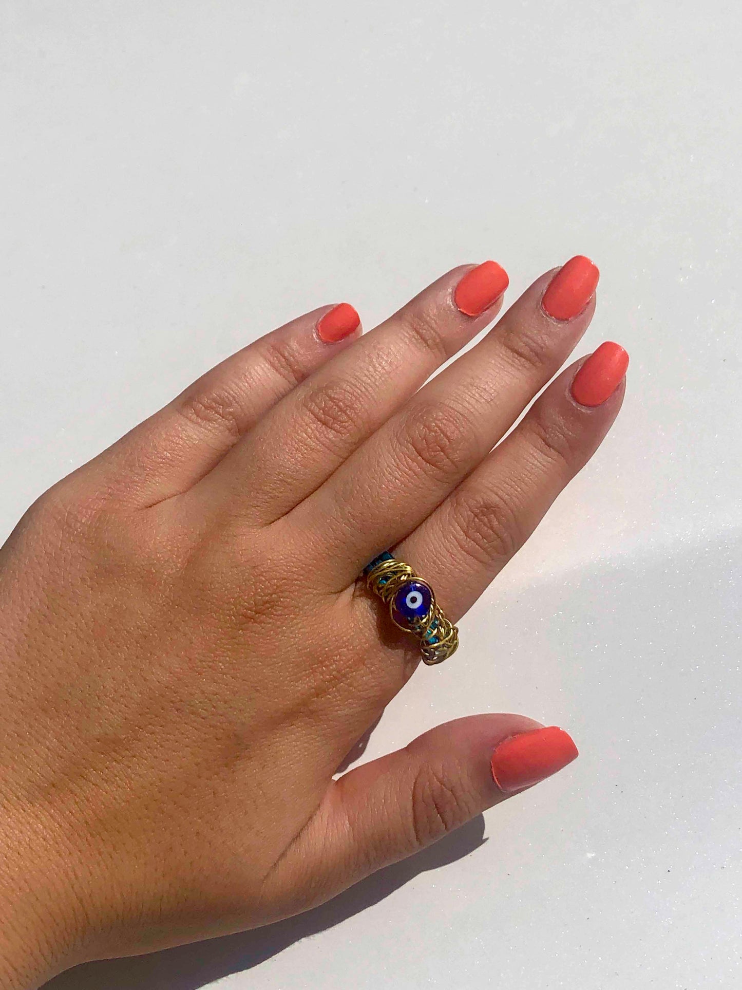 handcrafted ring made from thick blue wire wrapped base with an evil eye charm centerpiece wrapped in thin golden wire