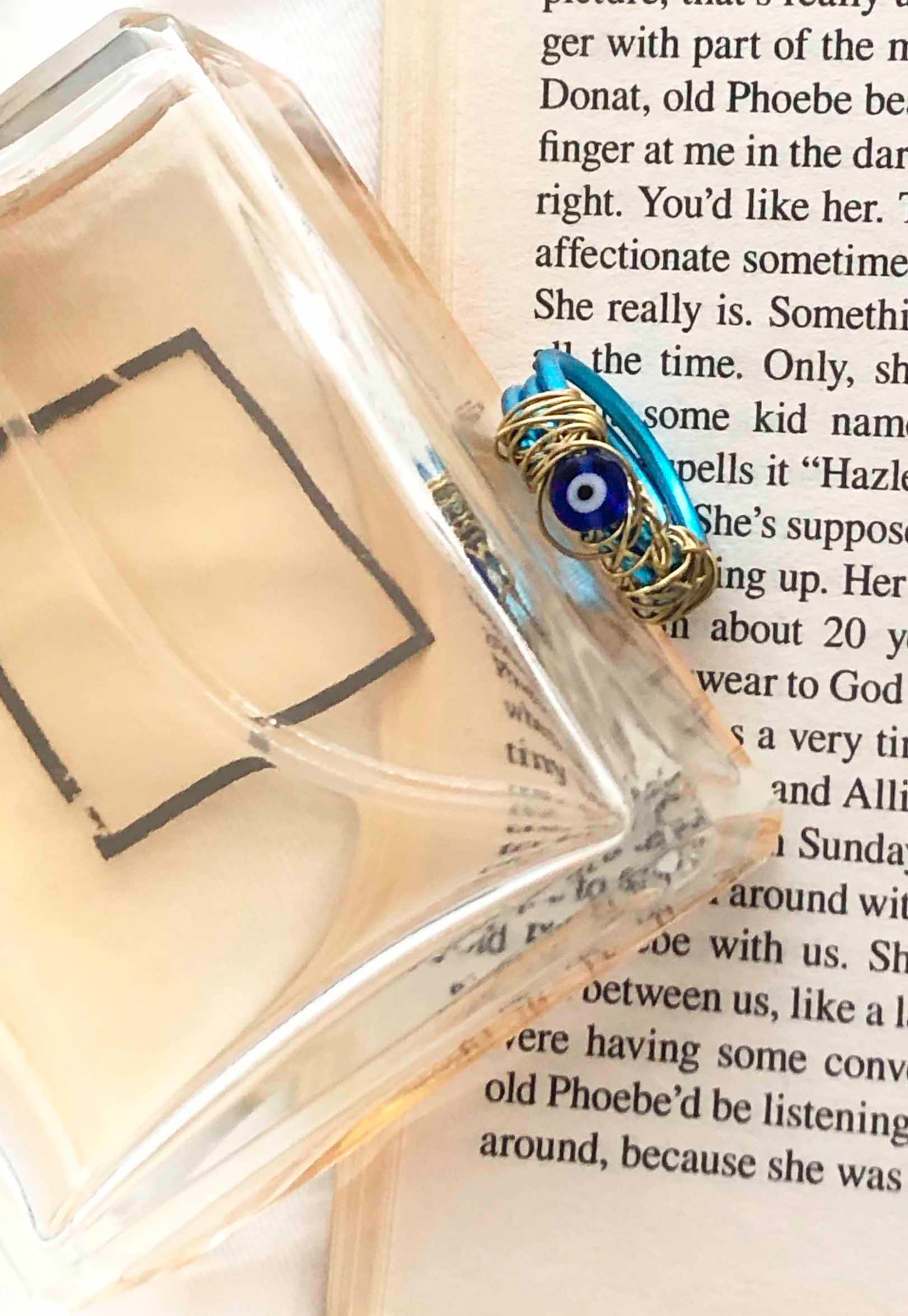 handcrafted ring made from thick blue wire wrapped base with an evil eye charm centerpiece wrapped in thin golden wire