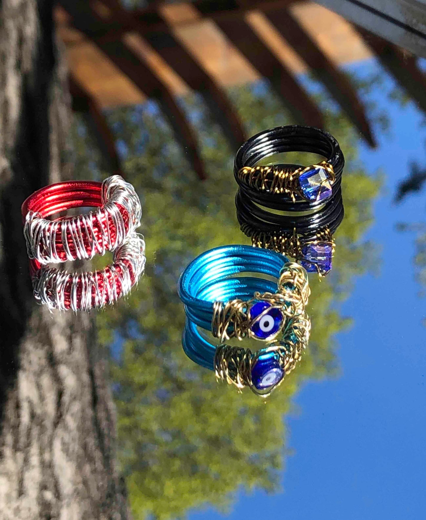 handcrafted ring made from thick blue wire wrapped base with an evil eye charm centerpiece wrapped in thin golden wire