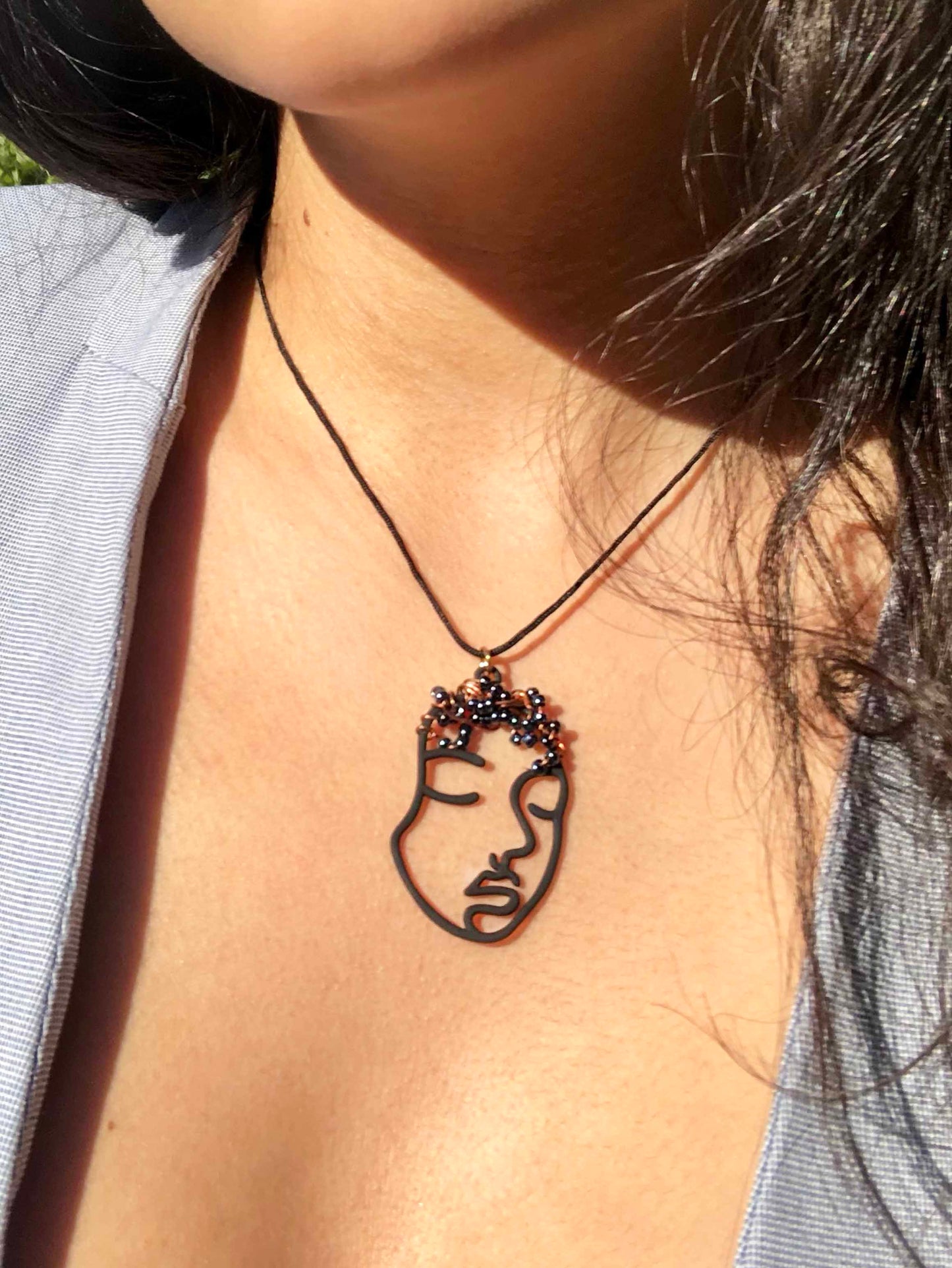 Hollowed out black face charm pendant necklace wire wrapped and beaded.