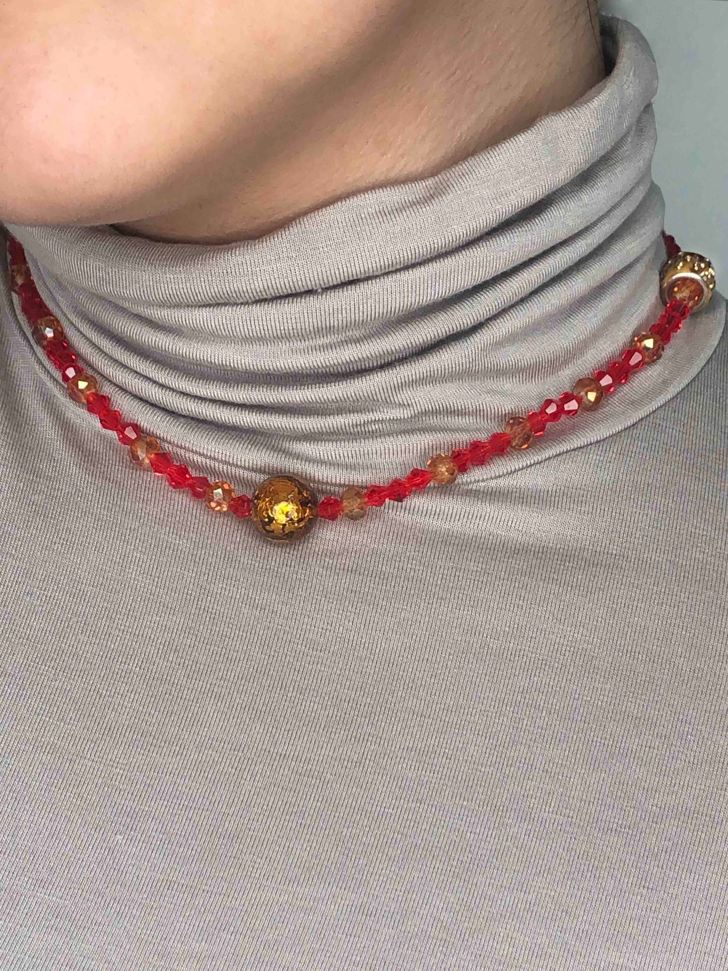 Handcrafted red and orange crystal beaded necklace with two golden rhinestone charms and a paper mache glass ball centerpiece.