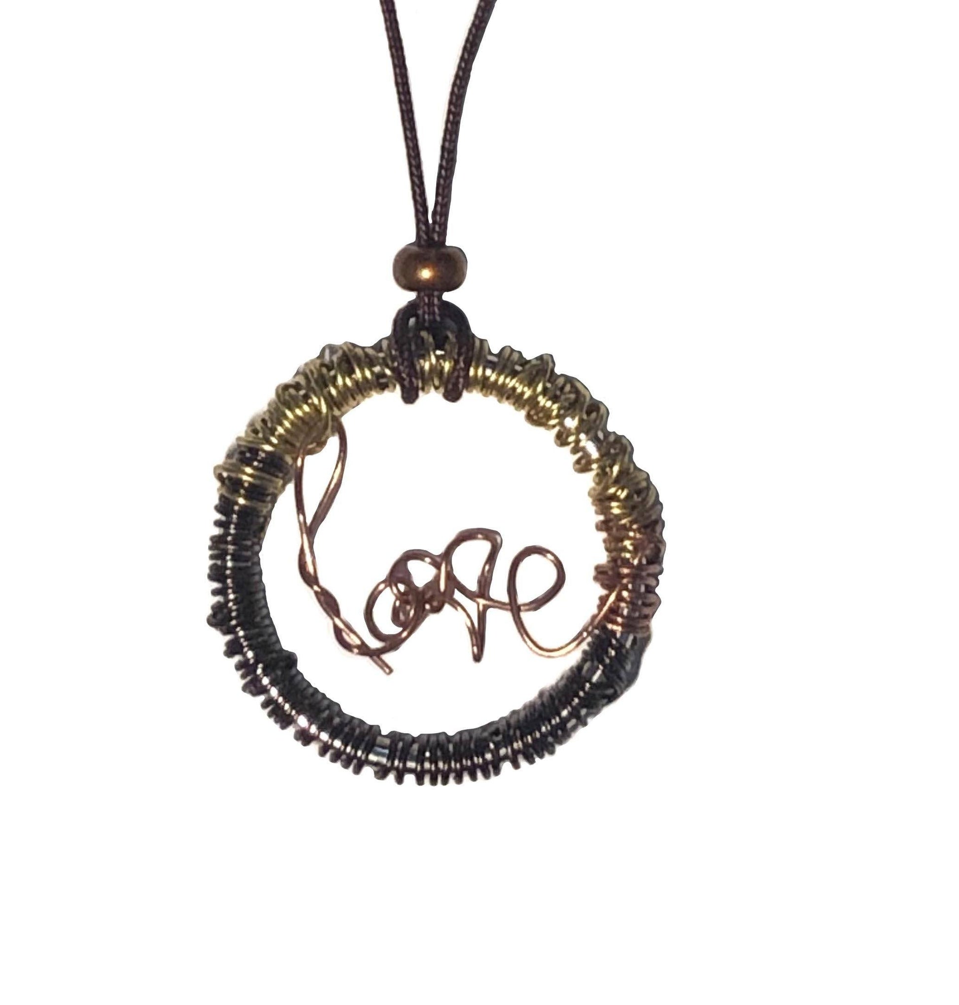 Golden and brown wire wrapped necklace with a copper wire that spells out love at the center, and a bronze bead on top.