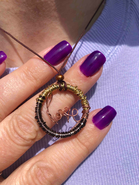 Golden and brown wire wrapped necklace with a copper wire that spells out love at the center, and a bronze bead on top.