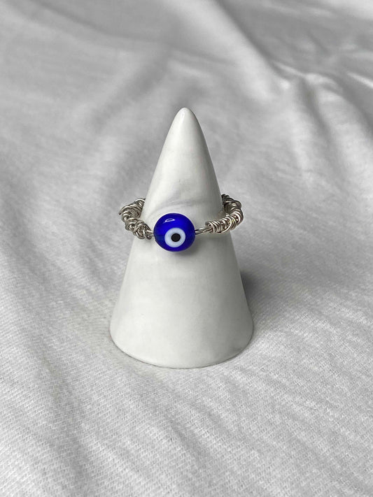 Handmade silver wire wrapped blue evil eye charm ring.