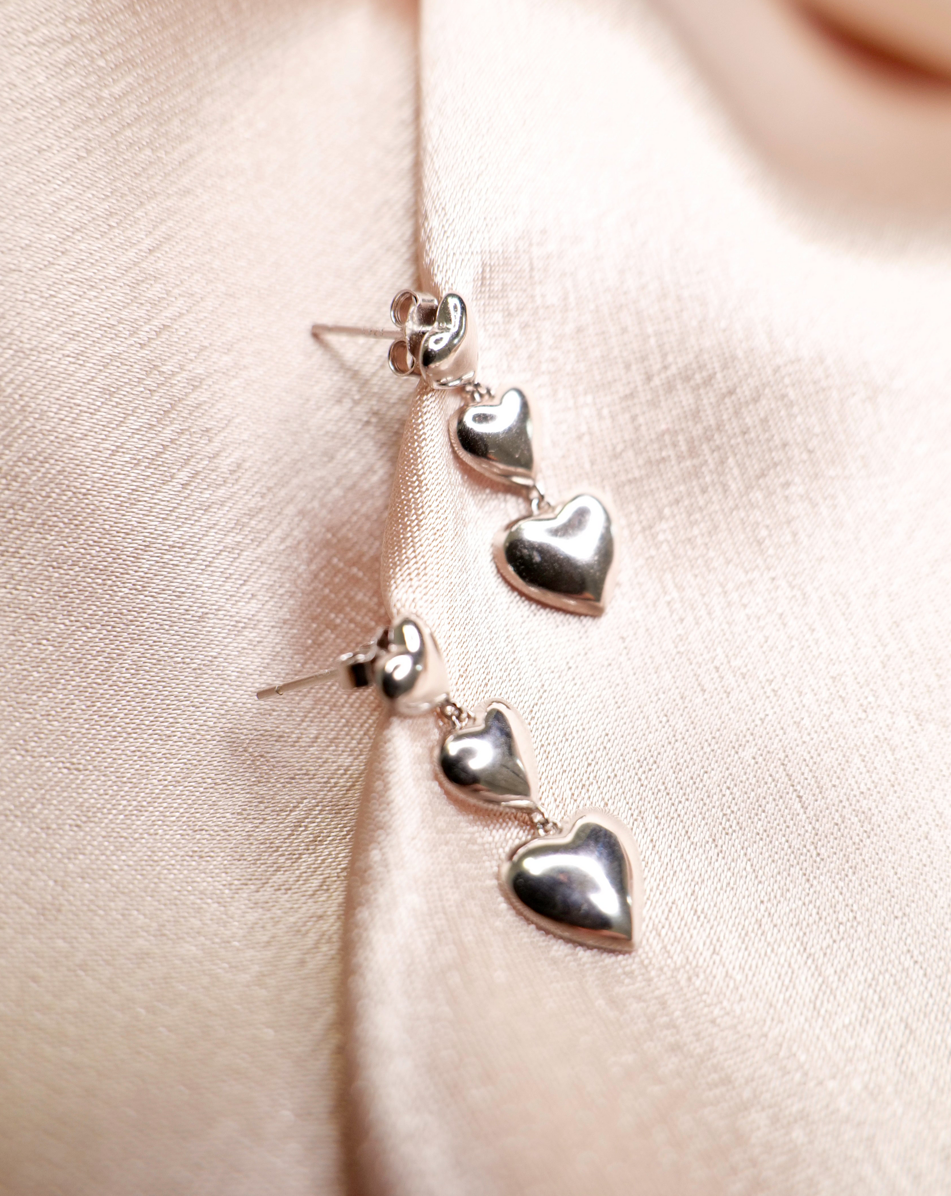 Close-up of heart-shaped dangle drop earrings. 925 sterling silver earrings.