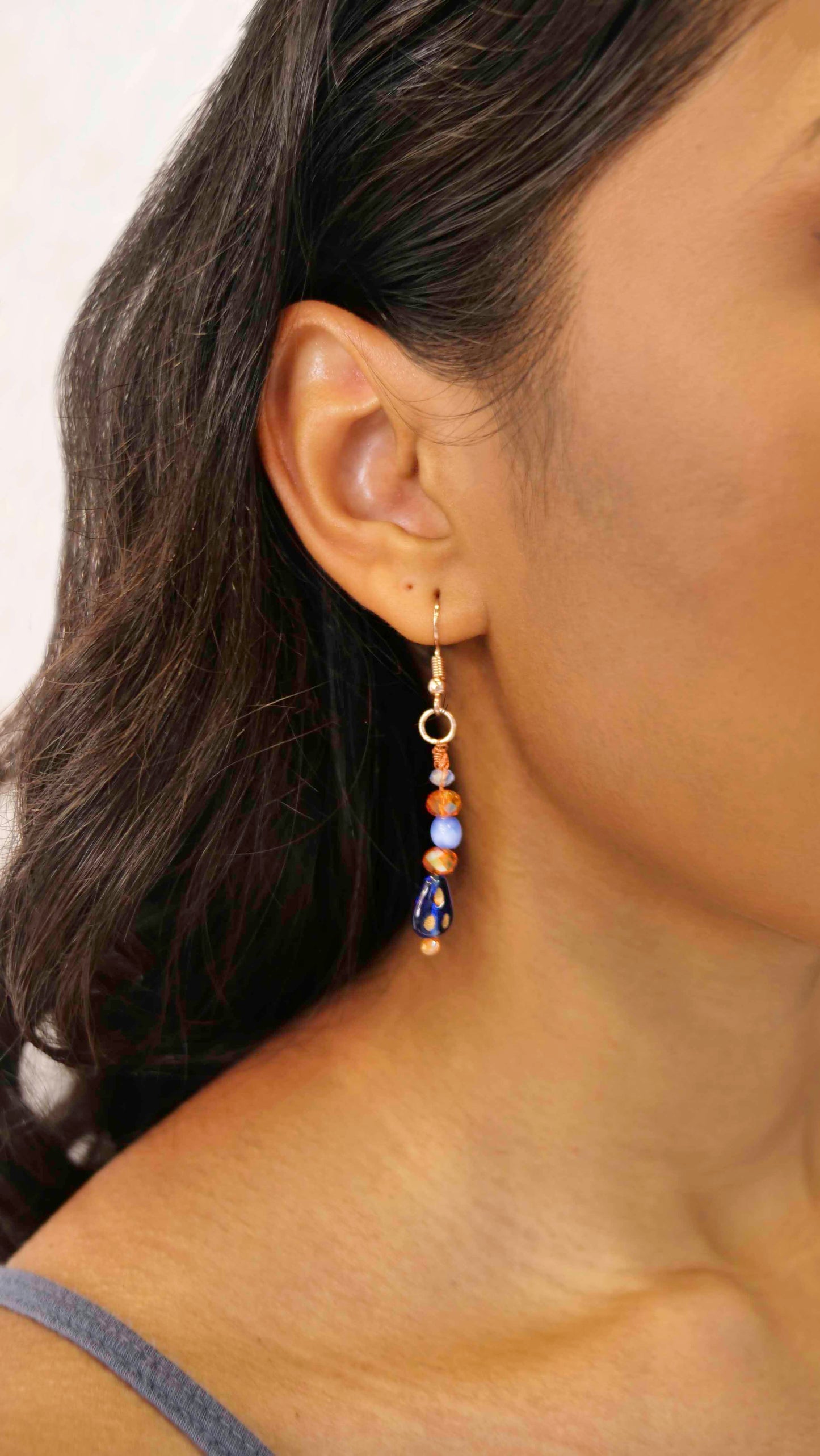 A handmade orange and blue crystal beaded pair of dangle drop earrings with blue glass charms.