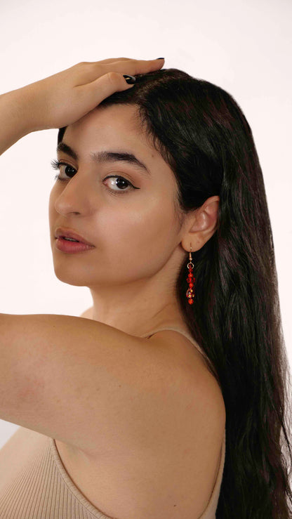 A handmade red and orange crystal beaded pair of dangle drop earrings with red glass charms.