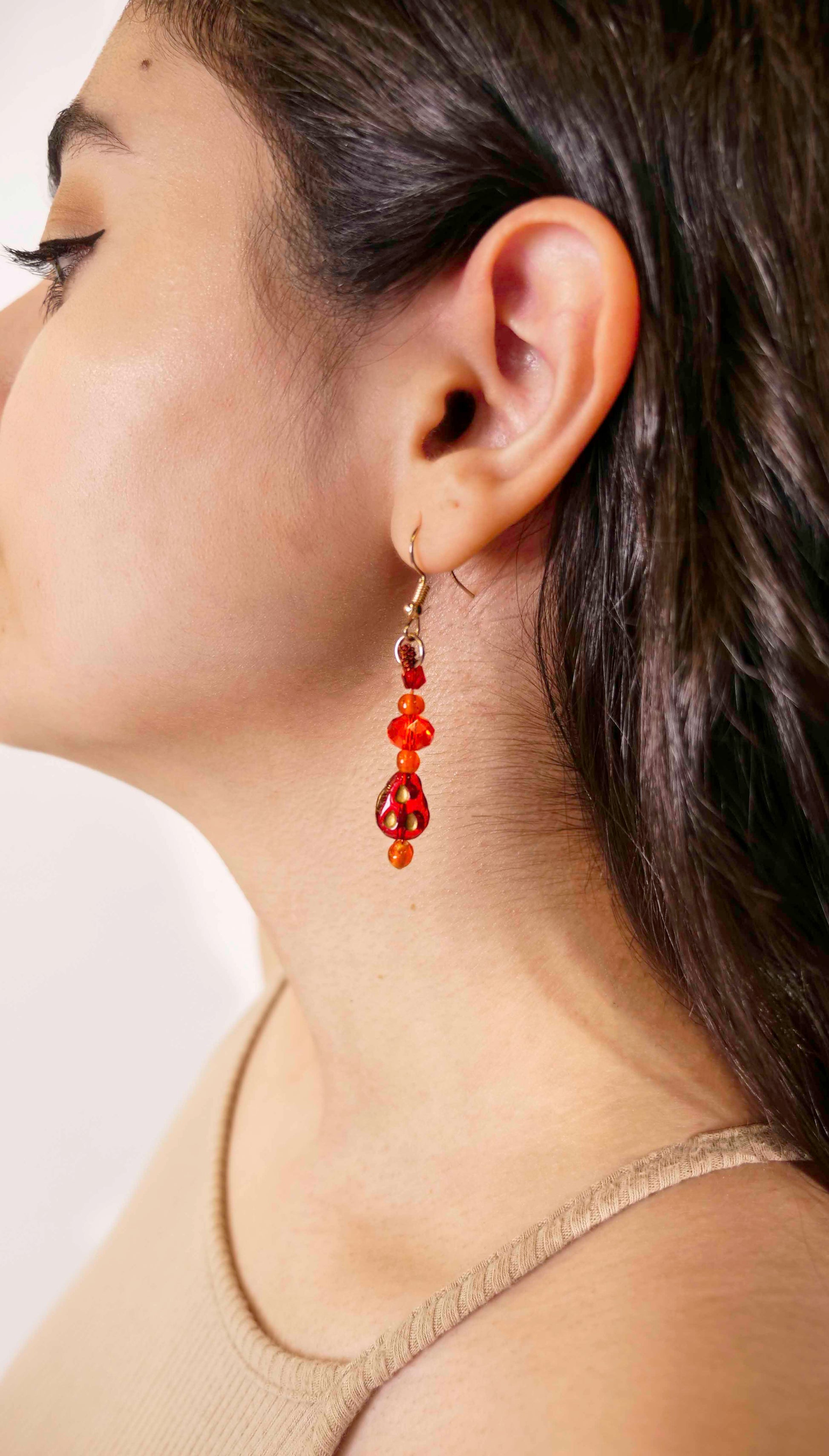 A handmade red and orange crystal beaded pair of dangle drop earrings with red glass charms.