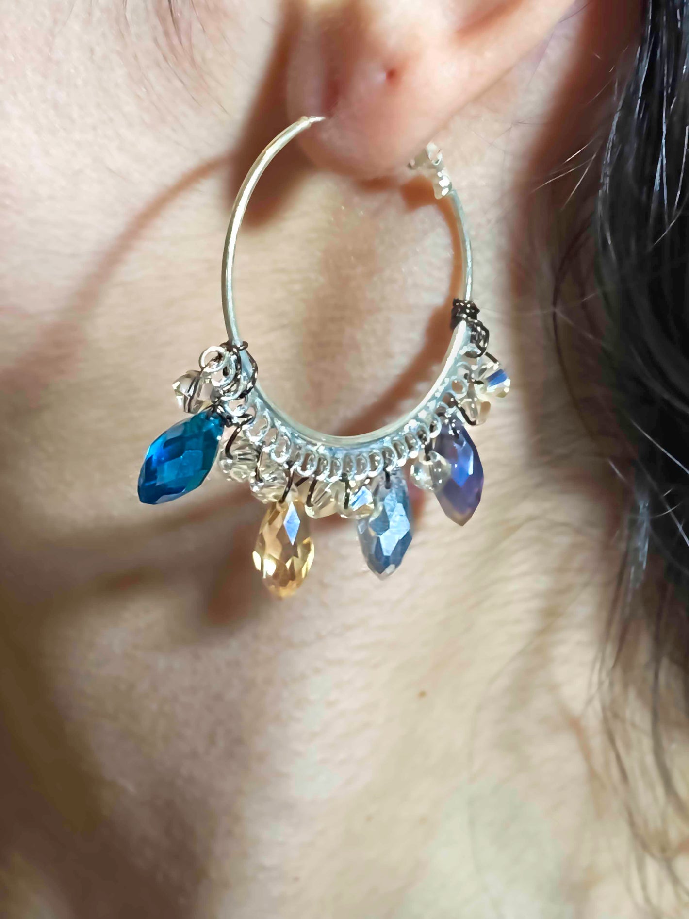 A handmade pair of blue and clear crystal beaded hoop earrings.