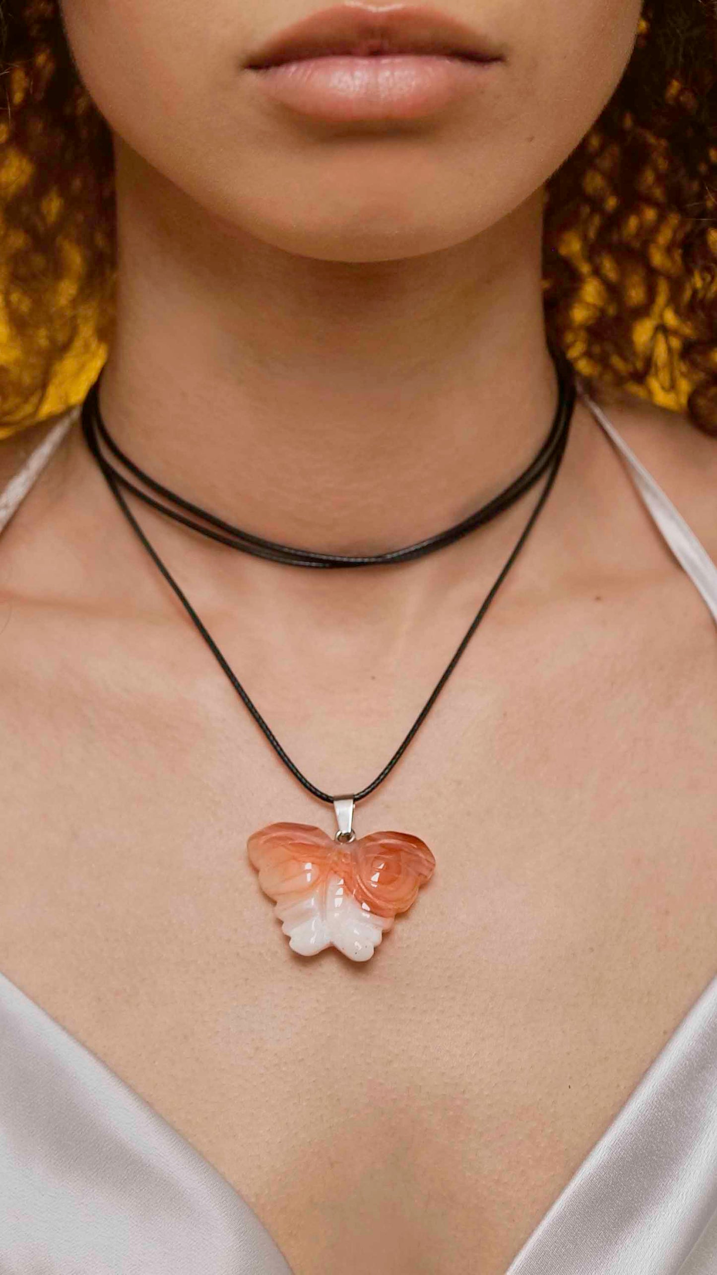 Handmade orange agate butterfly pendant necklace with a black vegan leather string.