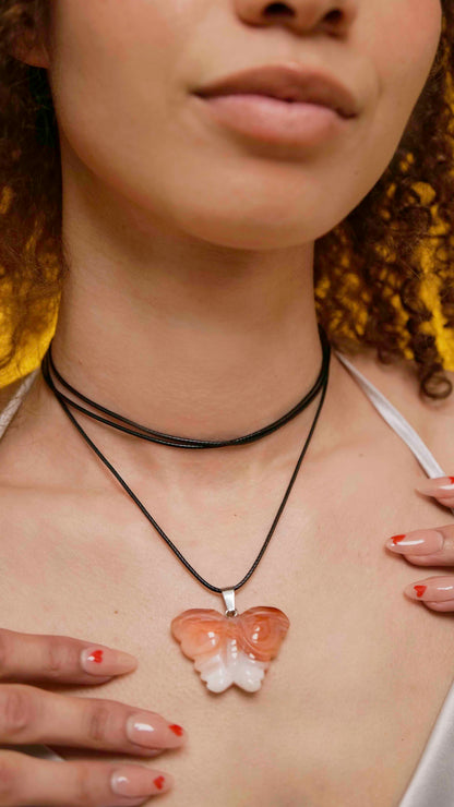 Handmade orange agate butterfly pendant necklace with a black vegan leather string.