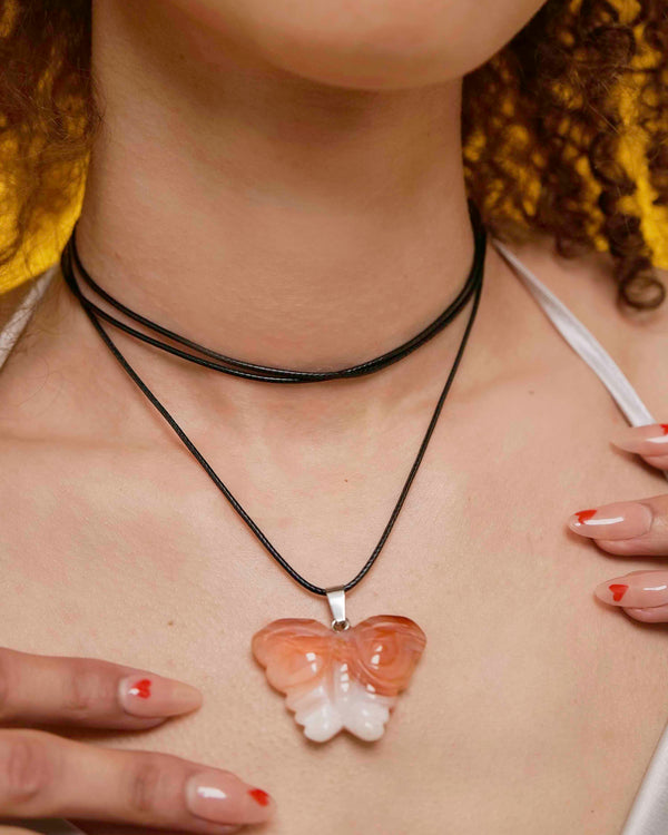 Handmade orange agate butterfly pendant necklace with a black vegan leather string.