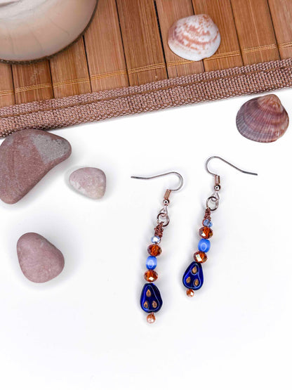 A handmade orange and blue crystal beaded pair of dangle drop earrings with blue glass charms.