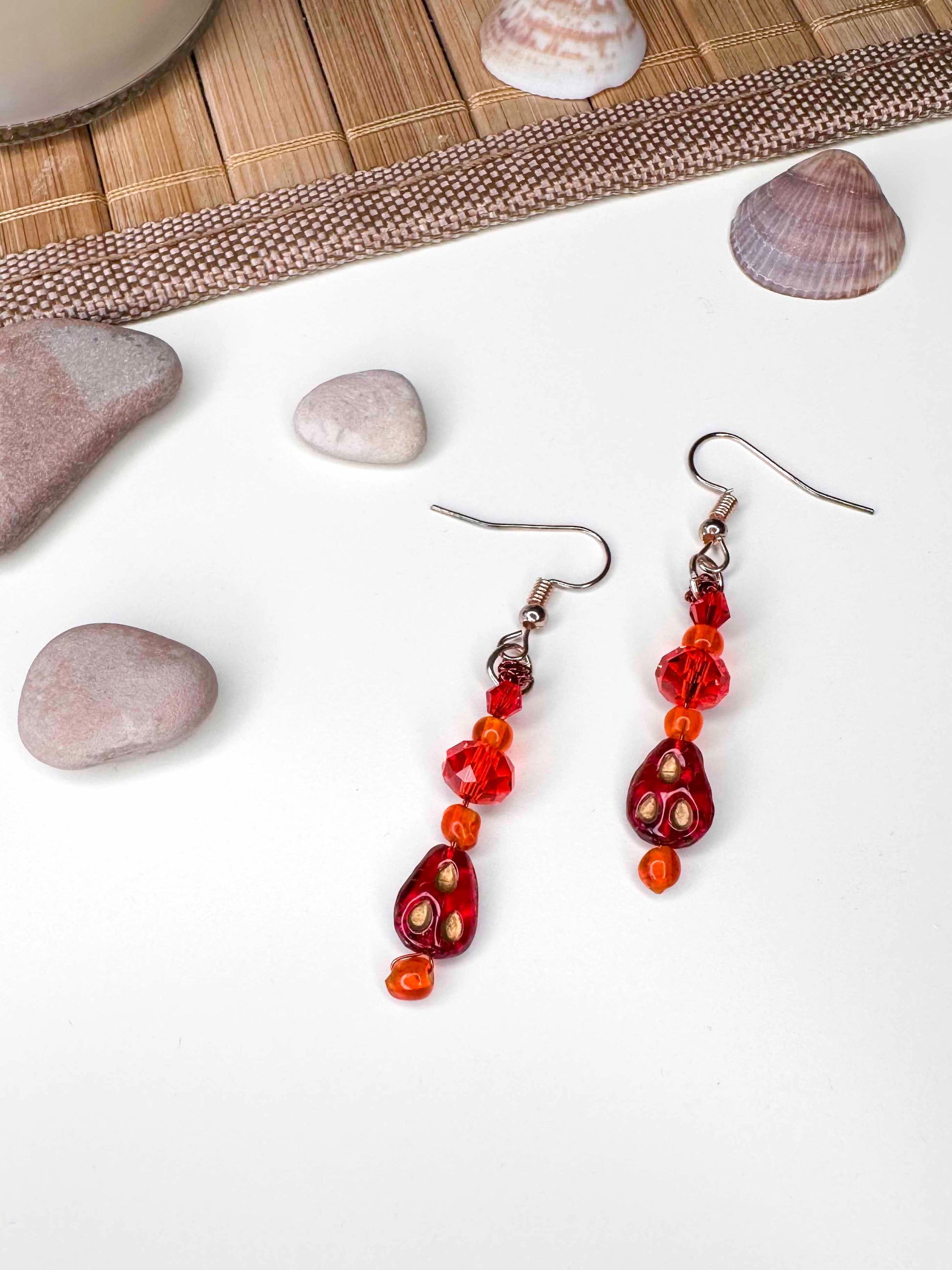 A handmade red and orange crystal beaded pair of dangle drop earrings with red glass charms.
