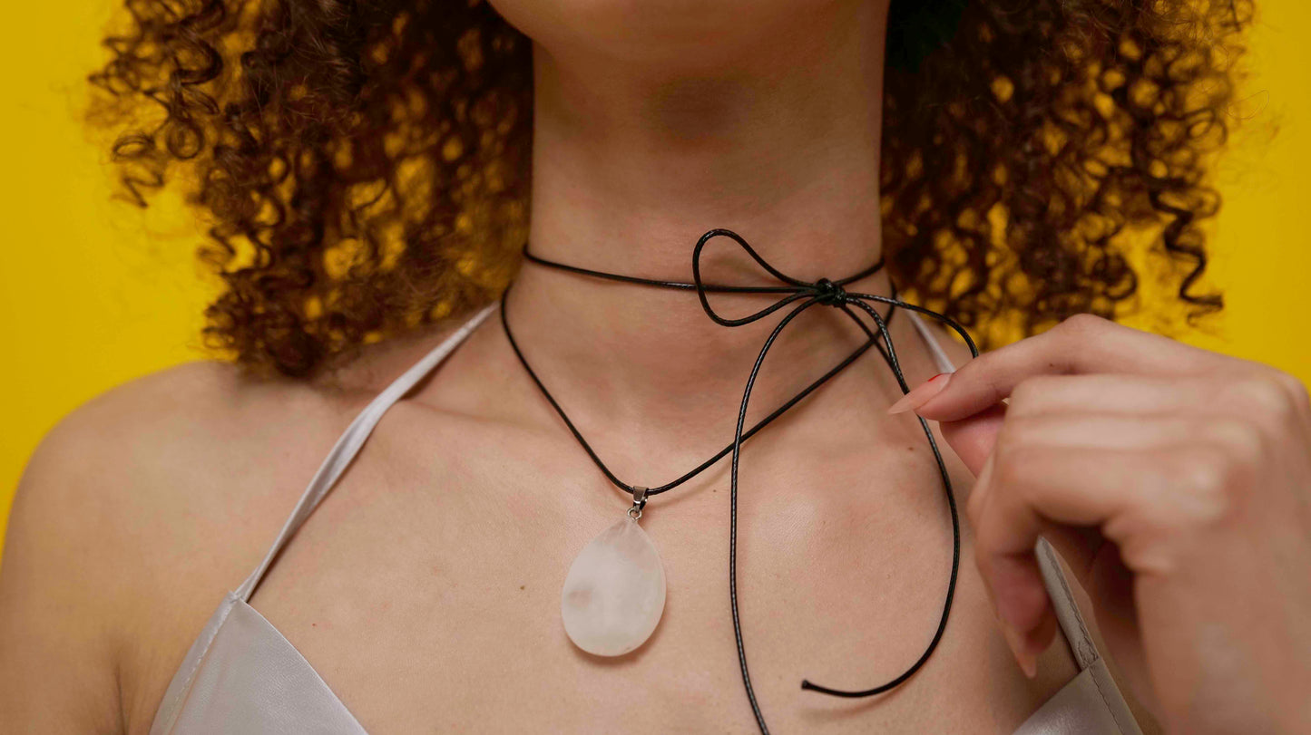 A handmade white jade teardrop pendant necklace with a black vegan leather string.