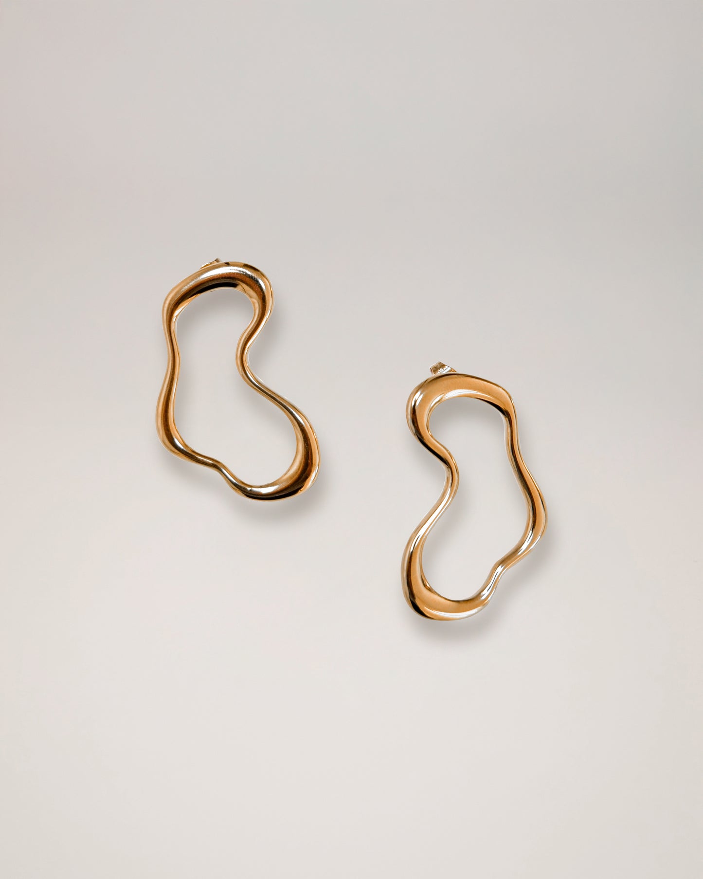 irregular hollow earrings, asymmetrical abstract earrings styled for evening wear, gold and silver finish
