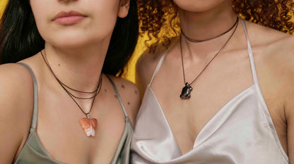 Handmade orange agate butterfly pendant necklace with a black vegan leather string, and a hematite turtle pendant necklace with brown leather string.