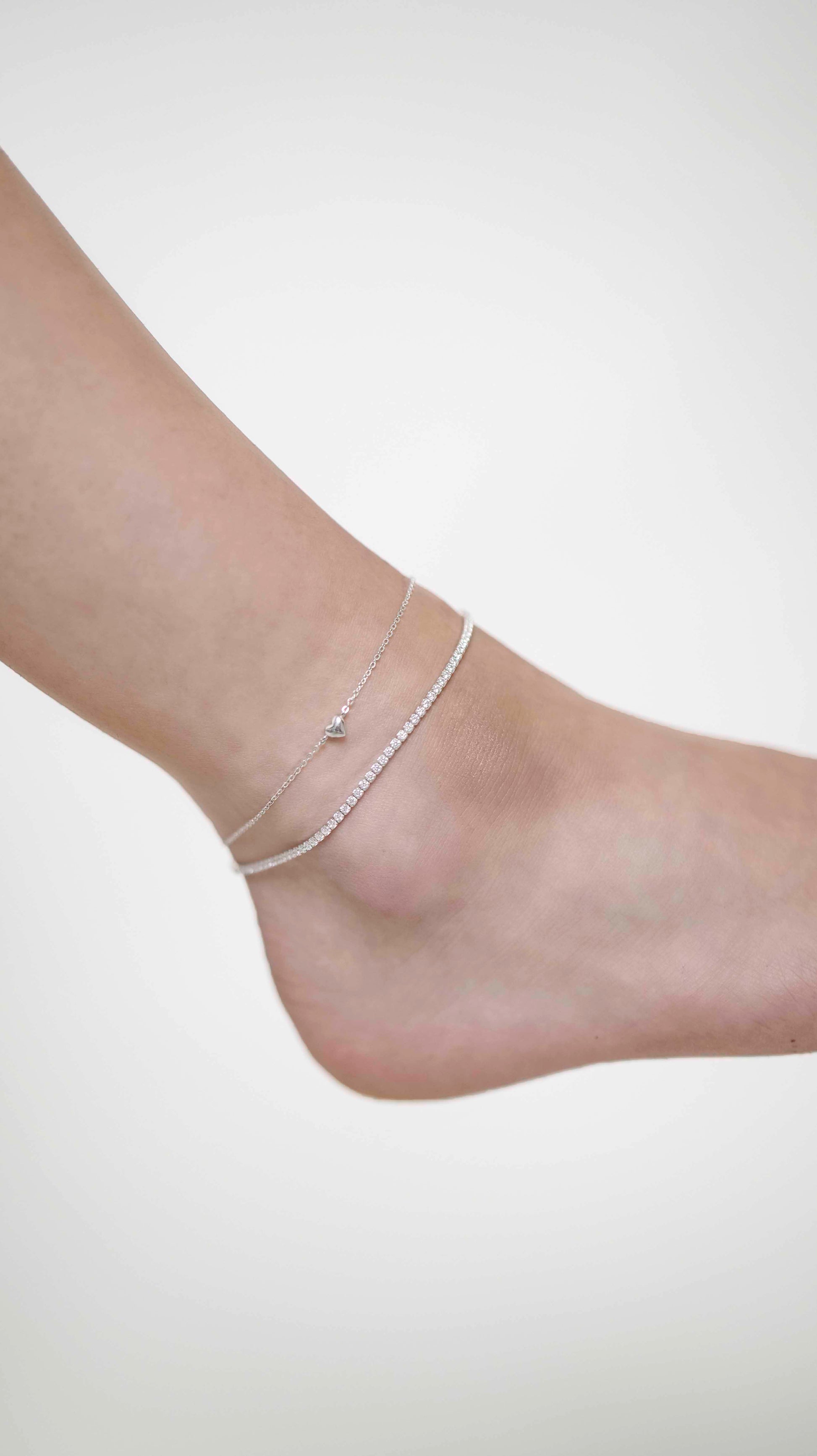 Sterling silver link chain anklet with a heart charm, and a Sterling silver zirconia stone tennis anklet.