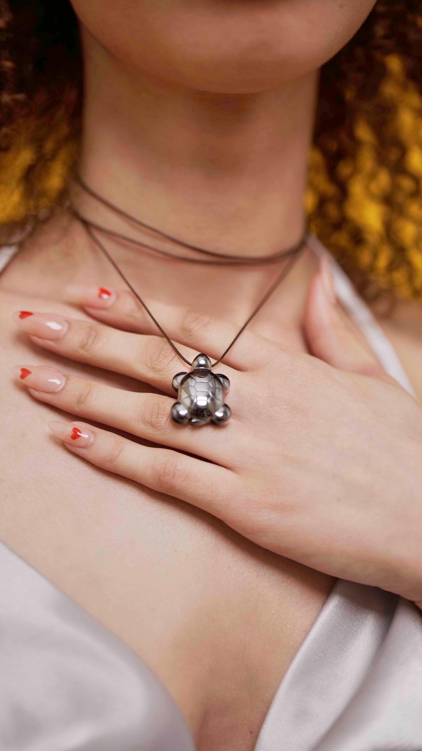 A handmade hematite turtle pendant necklace with brown leather string.